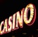 Brightly illuminated letters spell out 'CASINO' with glowing yellow bulbs and red outlines against a dark background.
